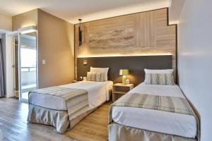 a hotel room with two beds and a window at SAN MARINO SUITES HOTEL By NOBILE in Goiânia +79 photos