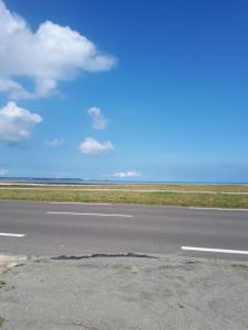 uma pista de aeroporto vazia com um céu azul e nuvens em Rose by the sea - Beach front sea views em Hirel