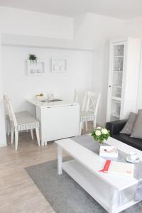 ein weißes Wohnzimmer mit einem Sofa und einem Tisch in der Unterkunft Ferienwohnung Steffens - "Mittelweg" in Grömitz