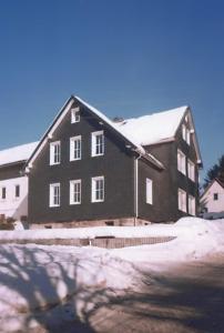 een groot zwart huis met sneeuw op het dak bij Ferienhaus Gäste Komfort Vesser in Vesser