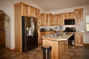 eine Küche mit einem schwarzen Kühlschrank und Holzschränken in der Unterkunft Upper Ranch - 100 Acre Mountain Views in Whitehall
