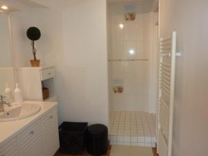 a white bathroom with a shower and a sink at La Suite Le Nôtre in Colleville-sur-Mer