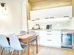 eine Küche mit weißen Schränken sowie einem Holztisch und Stühlen in der Unterkunft Apartment Górska 54 in Szczyrk