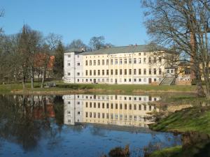 ein großes weißes Gebäude neben einem Wasserkörper in der Unterkunft Grafensuite auf Schloss Semlow in Semlow