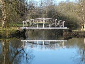 eine weiße Brücke über einen Fluss mit Reflexionen im Wasser in der Unterkunft Grafensuite auf Schloss Semlow in Semlow