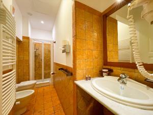 W łazience znajduje się umywalka, toaleta i lustro. w obiekcie Hotel La Plumeria w Cefalù