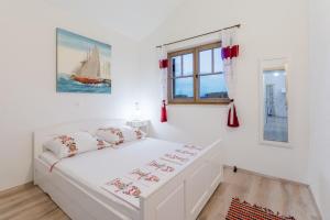 een witte slaapkamer met een wit bed en een raam bij Apartments Villa Kameja in Okrug Donji