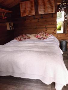 a bed in a log cabin with a white blanket at Le Chalet du Clos Giot in Saint-Vaast-la-Hougue