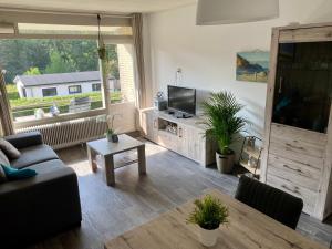 a living room with a couch and a tv and a table at Appartement Dishoek in Koudekerke