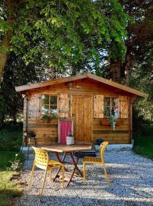 - une table de pique-nique et des chaises en face d'une cabine dans l'établissement Le Chalet du Clos Giot, à Saint-Vaast-la-Hougue