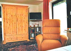 ein Wohnzimmer mit einem Stuhl und einem TV in der Unterkunft Ferienhaus Waldschrat - Komplettpreis in Zandt