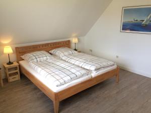 1 cama en una habitación con 2 lámparas y una foto en FeWo "Ahrens' Hüs", en Elsdorf-Westermühlen