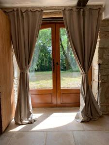 una ventana con cortinas delante de una puerta en Vue sur Gindou gîte, en Gindou