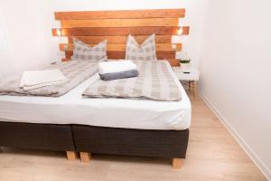 um quarto com uma cama grande e uma cabeceira em madeira em K2 Bungalow - Strandhaus Königsberger Allee 8 - FERIENDOMIZIL HOLLICH em Grömitz
