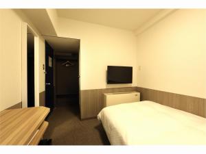 Sendai Business Hotel Ekimae - Vacation STAY 71907v في سيندايْ: غرفة فندقية بسرير وتلفزيون بشاشة مسطحة