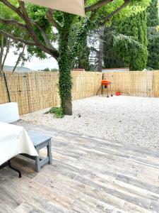 a patio with a tree and a bench and a fence at Il y a le Soleil, la Campagne et la Mer …1 in Martigues