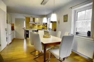 een keuken en eetkamer met een houten tafel en witte stoelen bij Strandläufer - 21841 in Zingst