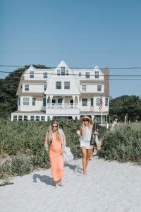 two women walking on the beach in front of a house at The Tides Beach Club in Kennebunkport