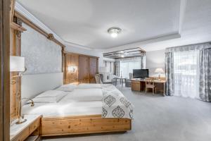 una camera da letto con un letto grande e una scrivania di Trofana Royal 5-Sterne Superior Resort a Ischgl