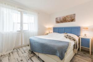 a bedroom with a blue bed and a window at Whg 10 - Laura in Zingst