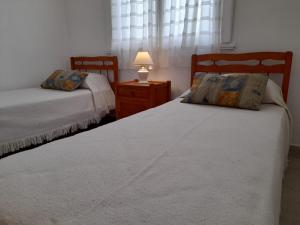 a bedroom with two beds and a lamp on a night stand at Hotel Rincón de Playa in Miramar