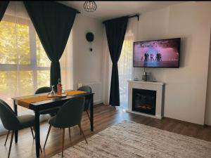 a living room with a table and a tv on the wall at Ama Apartament - Cota 1000 Sinaia in Sinaia