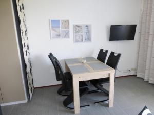 a dining room table with black chairs and a tv at An der Allee 20 B in Dahme