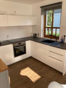 a kitchen with white cabinets and a sink and a window at Strand24 in Ostseebad Nienhagen