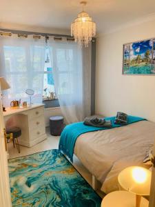 a bedroom with a bed and a desk and a chandelier at Stunning Seafront House with garden and private parking in Eastbourne
