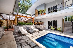 an outdoor patio with a swimming pool and a house at Hotel Elixir in Tamarindo