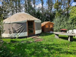 a yurt with a table and a bench in a field at La yourte au fonds du jardin in Xhoris