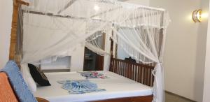 1 dormitorio con cama con dosel y cortinas blancas en Lavender mirissa en Mirissa