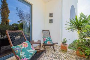 two chairs sitting on a patio with plants at Casa na Praia do Meco in Sesimbra