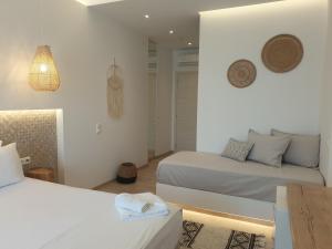 a white bedroom with two beds and a couch at Hotel Alexandra in Skala