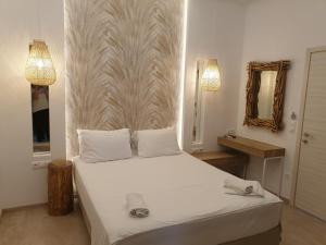 a bedroom with a white bed and a mirror at Hotel Alexandra in Skala