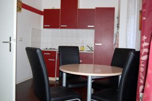 eine Küche mit einem Tisch, Stühlen und roten Schränken in der Unterkunft Ferienwohnung am Saalebogen in Calbe