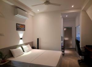 1 dormitorio con 1 cama blanca y ventilador de techo en Weligama Bay Watsila Resort, en Weligama