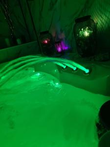 a green bath tub with lights in a bathroom at Luxury 9ine THE EXCLUSIVE JACUZZI APARTMENT in Birmingham
