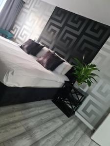 a bedroom with a bed with pillows and a plant at Luxury 9ine THE EXCLUSIVE JACUZZI APARTMENT in Birmingham