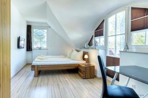 a bedroom with a bed and a desk and windows at Dat Ferienhus Sophia in Zingst