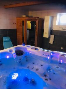 een blauw bad in een badkamer met een spiegel bij Gîte Spa Sauna Piscine CÔTÉ VERGER Merxheim Alsace in Merxheim