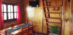 a dining room with a table and chairs and a television at Cabañas Pulmahue in Colón