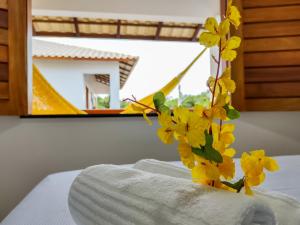 wazon z żółtymi kwiatami na górze łóżka w obiekcie Pousada Brisas w mieście Jijoca de Jericoacoara