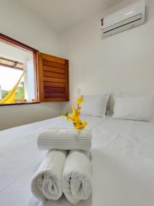 Un dormitorio con una cama blanca con toallas. en Pousada Brisas en Jijoca de Jericoacoara