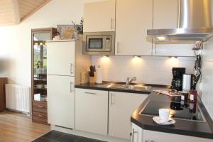 eine Küche mit weißen Schränken und einem Waschbecken in der Unterkunft "Ferienhaus I - Hof Westensee" in Grömitz
