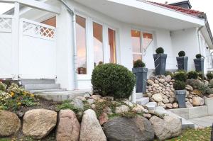 Uma casa branca com pedras à frente. em IW - Komfort-Apartment Im Winkel 13 - FERIENDOMIZIL HOLLICH em Grömitz