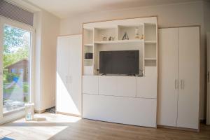 a living room with a tv in a white cabinet at Scheune 8 in Gollendorf