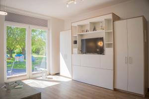 a living room with a tv and a white cabinet at Scheune 8 in Gollendorf