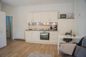 a kitchen with white cabinets and a desk and a table at Scheune 8 in Gollendorf