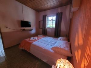 ein Schlafzimmer mit einem großen Bett und einem Fenster in der Unterkunft Chácara dos Pássaros in Gonçalves